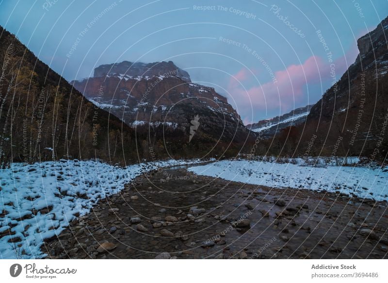 Fast river flowing through mountain valley forest landscape rocky wild stream terrain cloudy cold winter nature water splash stone rapid shallow peak scenic