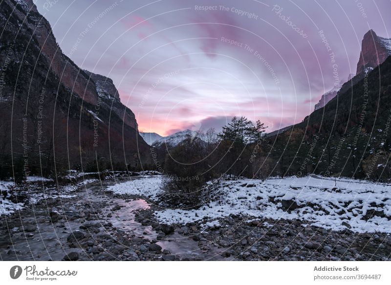 Fast river flowing through mountain valley forest landscape rocky wild stream terrain cloudy cold winter nature water splash stone rapid shallow peak scenic