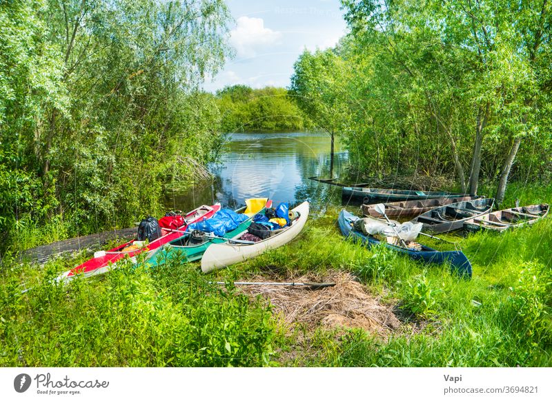 Many loaded kayaks with cargo on river boat water canoe trees activity summer vacation travel bags fishing boat bushes recreation kayaking leisure nature shore