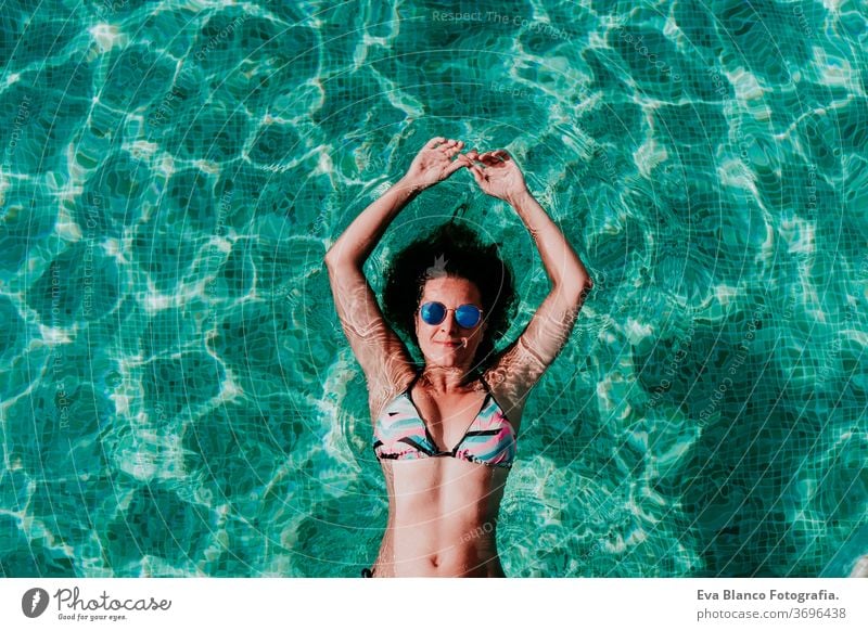 top view of happy young woman floating in a pool. summer and fun lifestyle underwater swimming bubbles caucasian dive clear health light action wet swimmer blue