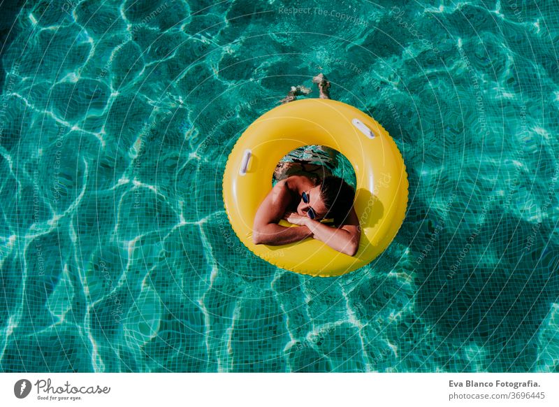 top view of happy young woman floating in a pool in a yellow donuts. summer and fun lifestyle inflatable swimming bubbles caucasian dive clear health light