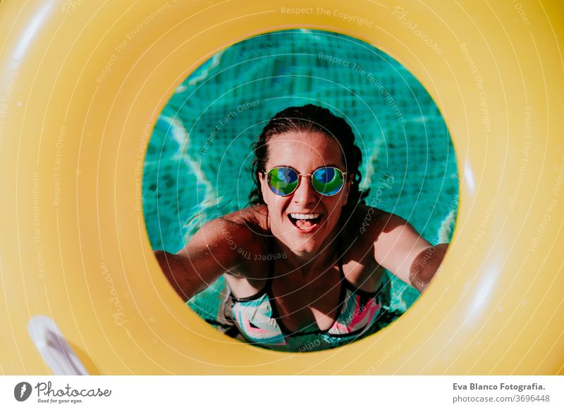 top view of happy young woman in a pool holding a yellow donuts. summer and fun lifestyle inflatable swimming bubbles caucasian dive clear health light water