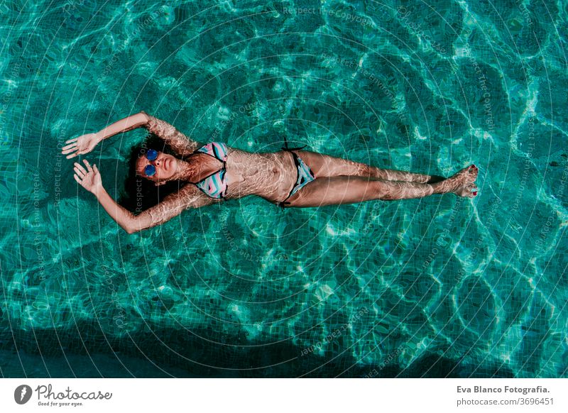 top view of happy young woman floating in a pool. summer and fun lifestyle underwater swimming bubbles caucasian dive clear health light action wet swimmer blue