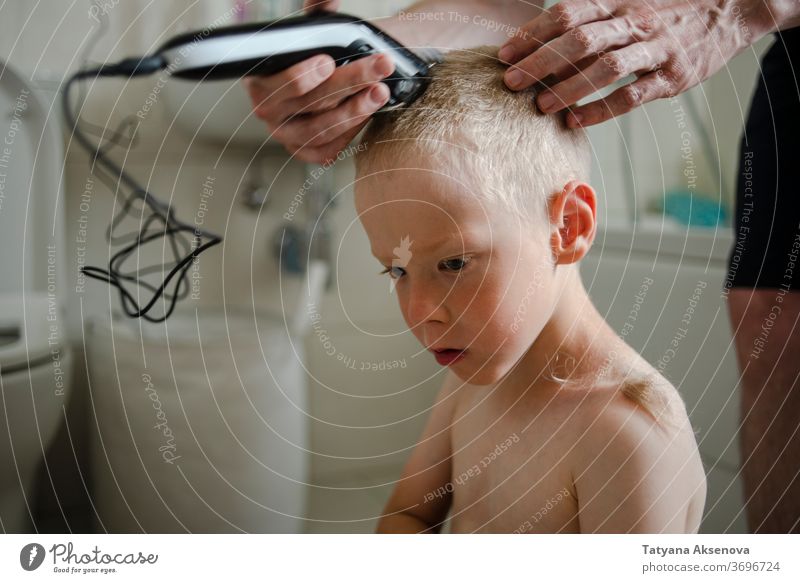 Father making haircut for son at home hairstyle child care machine bathroom family hand hairdresser man trimmer face young quarantine head caucasian male people