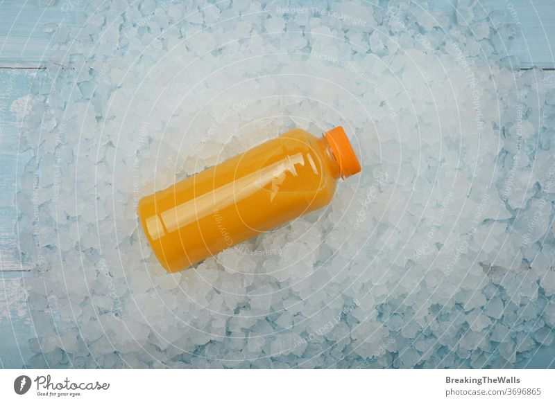 Bottle of fresh orange juice over crushed ice Orange bottle one plastic PET full squeezed pressed background closeup blue white cold frozen fruit vitamin