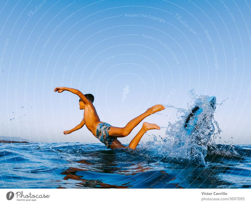 A young boy learning in body board outdoors in the shoreline in a sunny day of summer bodyboarder child holiday vacation leisure lifestyle surfboard surf-riding