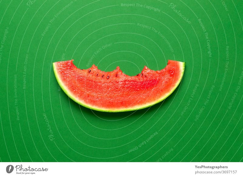 Slice of watermelon isolated on a green background. Bitten slice of watermelon top view. above view bitten colored colorful cut cut out detox diet eat eaten