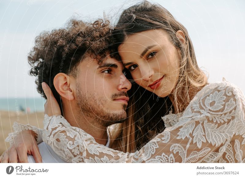 Happy newlywed couple hugging on beach romantic happy cuddle gentle enjoy together relationship love embrace marriage tender cheerful sensual smile content