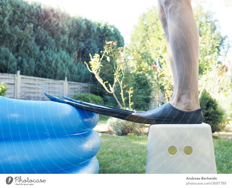 Man with flippers stands in front of a small inflatable pool. sportsman training athletic professional fit aqua fitness athlete swimwear handsome guy diver