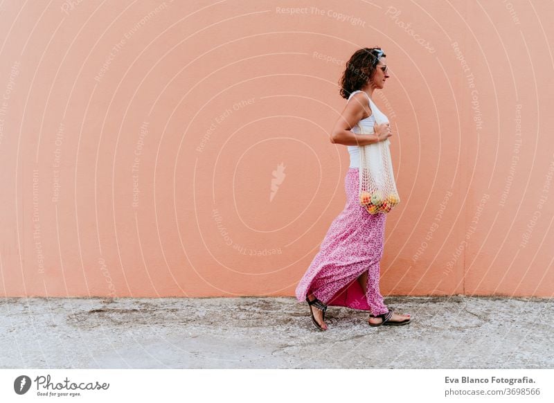 woman walking by the city, holding a cotton bag with fruit. Eco friendly, zero waste concept caucasian urban consumer green environment buy money pursed reduce