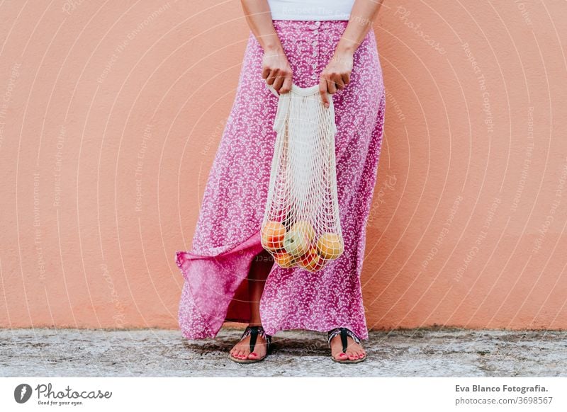 woman walking by the city, holding a cotton bag with fruit. Eco friendly, zero waste concept caucasian urban consumer green environment buy money pursed reduce