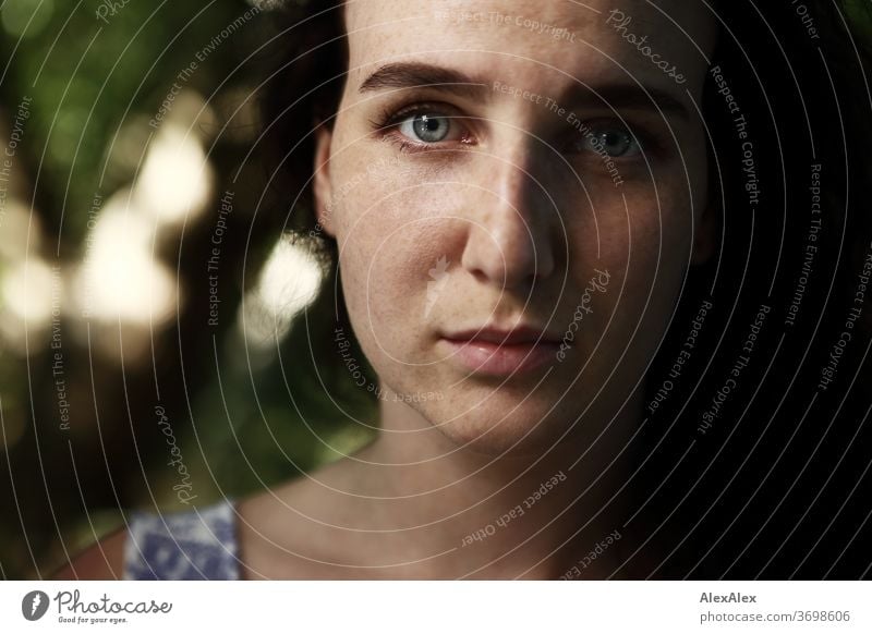 Close portrait of a freckled woman in a forest in summer Delicate Shadow Light Athletic Feminine empathy Emotions emotionally Looking into the camera