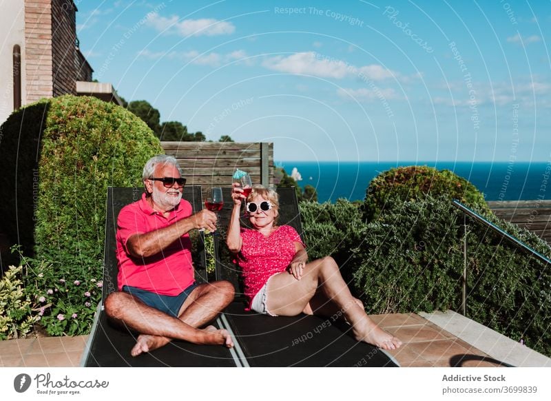 Content elderly couple on deck chairs summer vacation cocktail tropical senior relax together deckchair lying terrace beverage chill enjoy holiday drink