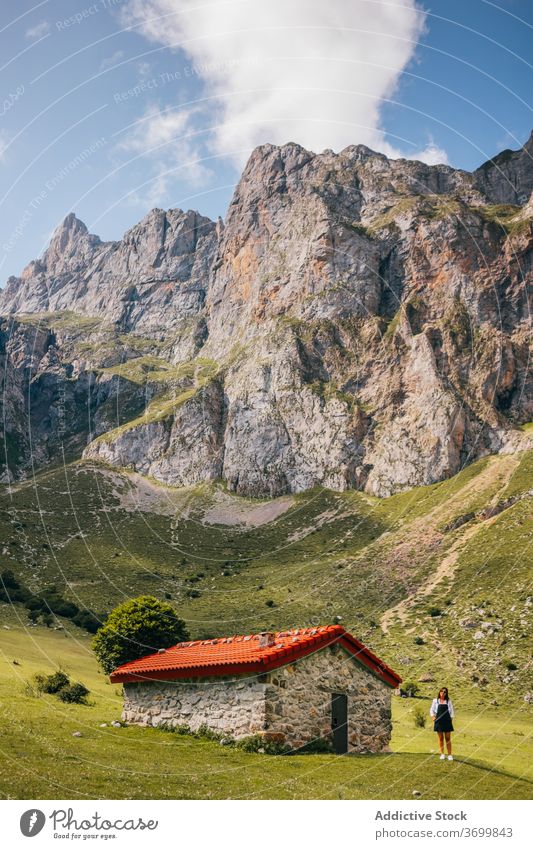 Female standing near stone house in green mountain valley woman range travel residential hiking holiday picos de europa cabin meadow landscape asturias spain