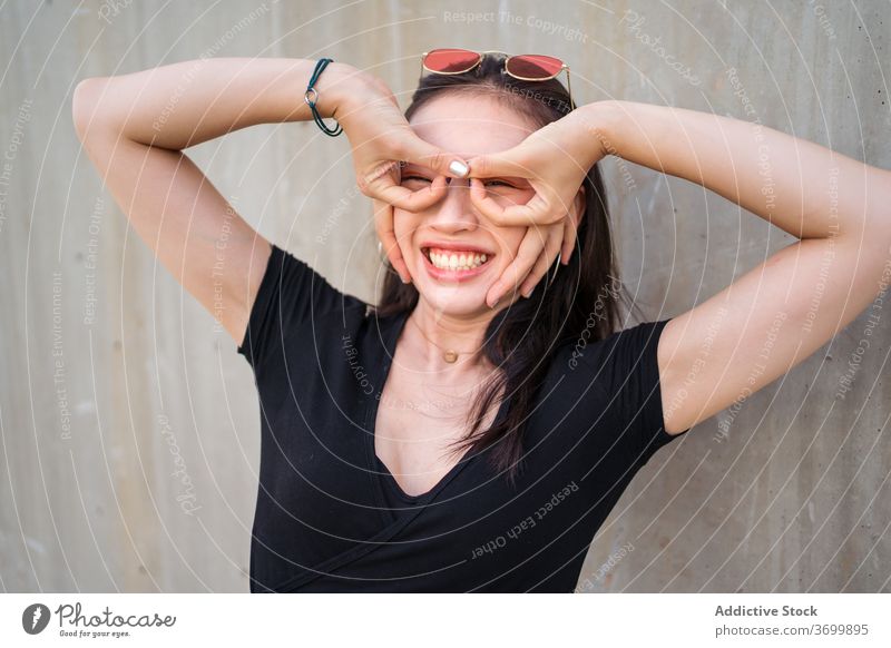 Smiling ethnic woman having fun in city grimace make face funny humor glad delight positive female asian concrete building street joy relax daytime optimist