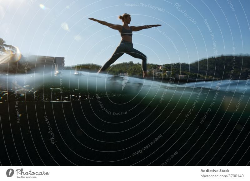 Woman doing yoga in Warrior pose warrior pose woman asana sea tranquil peaceful virabhadrasana harmony practice female pier water healthy coast idyllic ocean