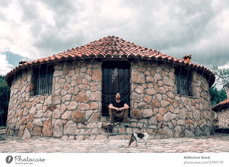 Carefree traveling man near stone building cobblestone city traveler relax stroll vacation summer male aged tourist sit rest old town exterior trip step stair