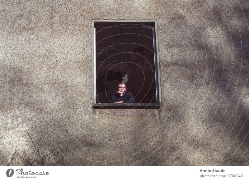 Young man in a dilapidated house looks out the window young looking old chin hand architecture ruin person male abandoned caucasian portrait building wall