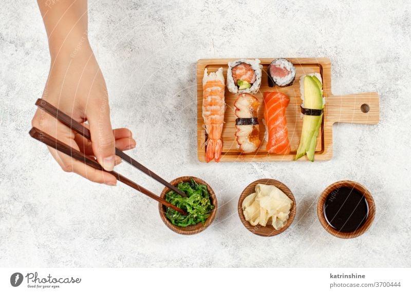 Top view of hand taking roll with chopsticks from a plate sushi ready to eat eating Sashimi Rolls sushi bar dinning Japanese Culture Seafood top view Asian