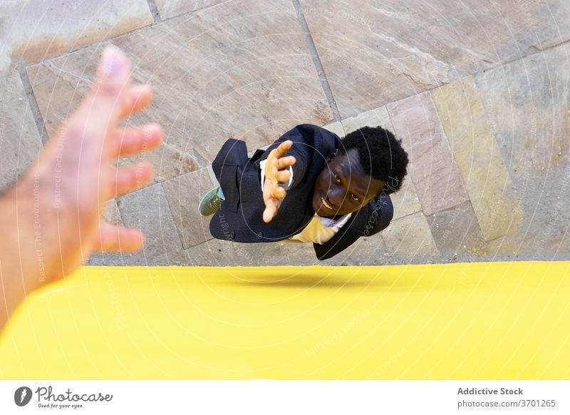 Black man jumping on city street help hand support together person reach building multiethnic multiracial diverse black african american barcelona spain stone