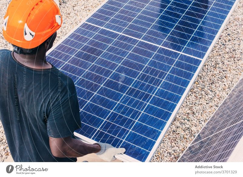 Ethnic man with solar panel on construction site industrial alternative work sustainable renewal ethnic black african american together sunny area modern walk