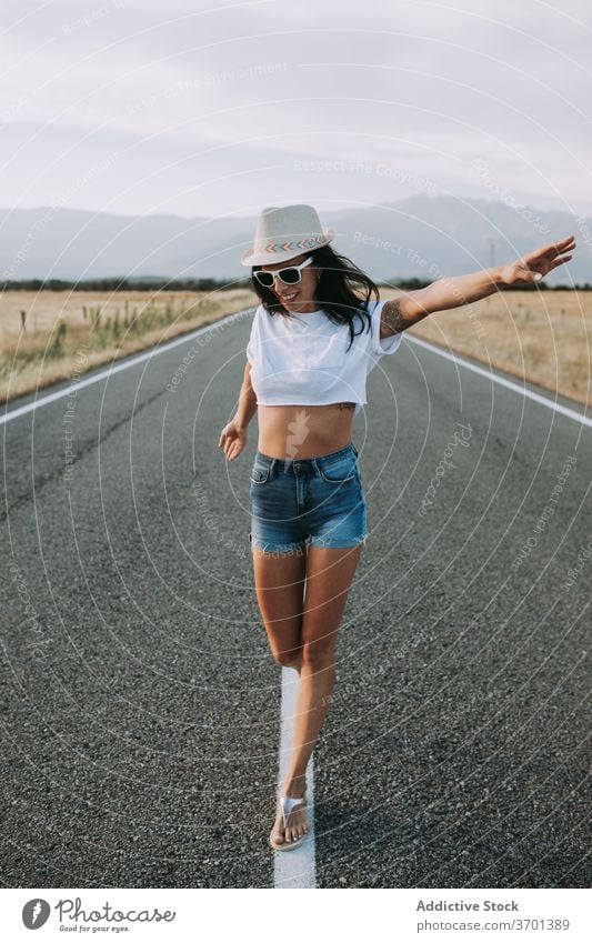 Carefree woman walking along road carefree enjoy freedom empty traveler serene mountain female summer roadway landscape tourism trip vacation asphalt adventure