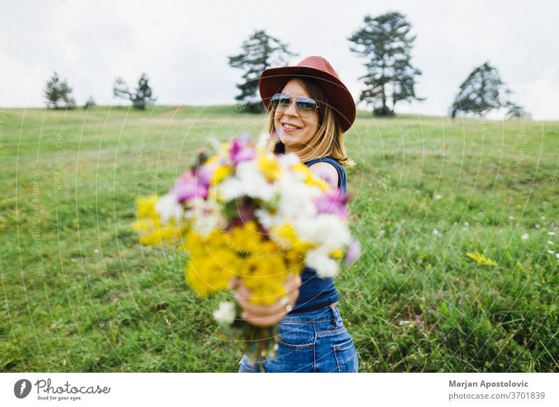 Young woman holding flower bouquet  in the field adult beautiful beauty bunch carefree casual charm colorful country cute environment fashionable female