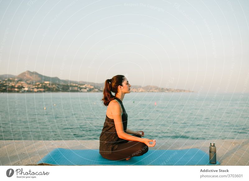 Flexible woman meditating in Lotus pose meditate lotus pose yoga sunset sea mindfulness mat harmony relax female seascape asana tranquil healthy padmasana mudra