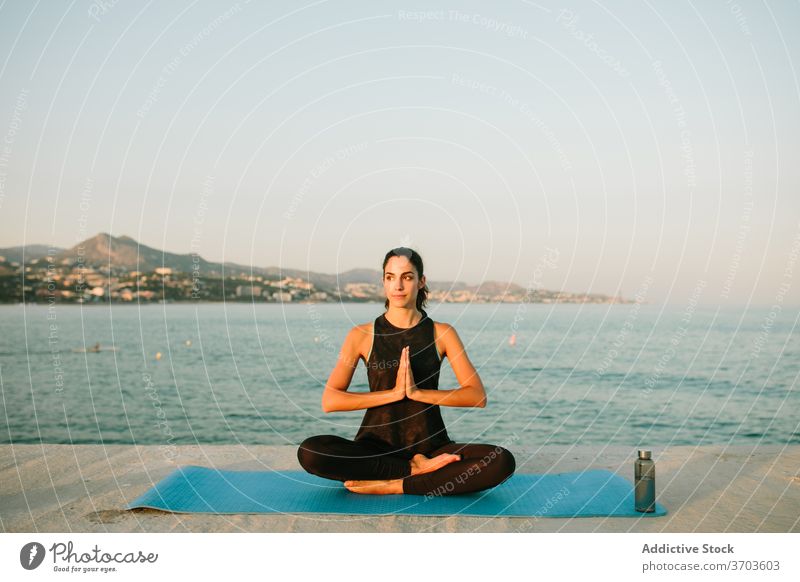 Flexible woman meditating in Lotus pose meditate lotus pose yoga sunset sea mindfulness mat harmony relax female seascape asana tranquil healthy padmasana mudra