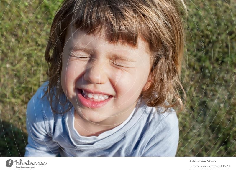 Cute little child in field make face grimace cheerful weekend funny kid summer having fun cute joy happy rest grass adorable relax sit childhood playful sweet