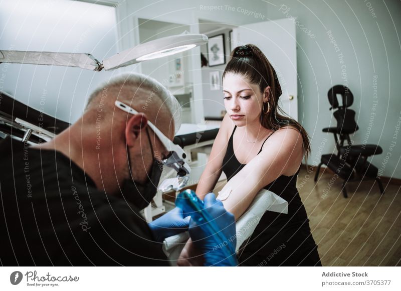 Male tattooist making tattoo in salon master man machine apply work design needle male studio sterile glove protect mask ink art client pigment job guy