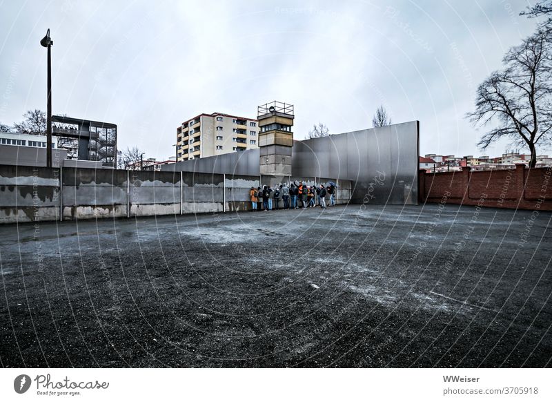 A group of young tourists in close contact with the Berlin Wall The Wall Traces of fomer wall Wall (barrier) memorial Monument Tourists Near gravel surface