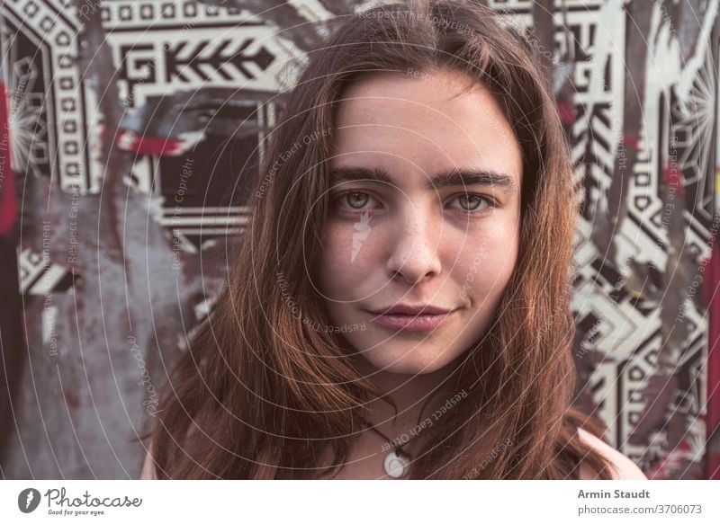 Portrait of a young smiling woman in front of a wall with torn posters portrait smile beautiful closeup texture pattern grunge happy confident candid teen