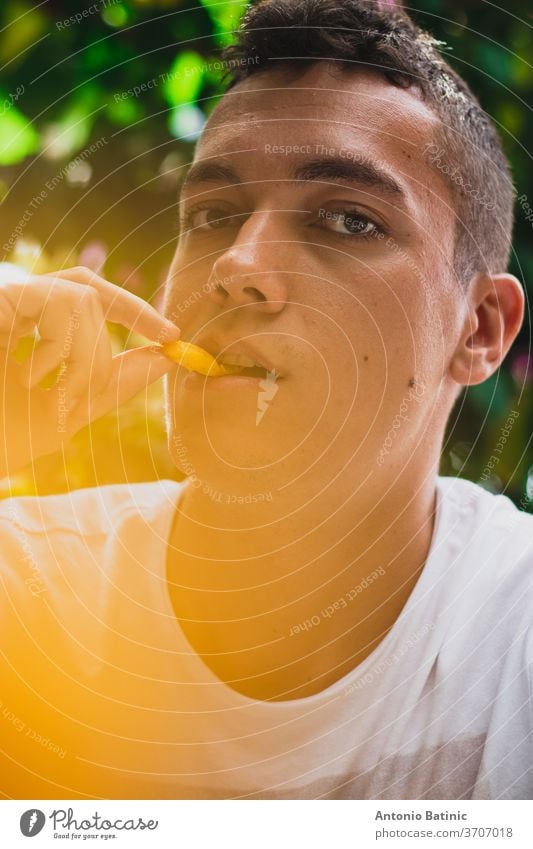 Closeup of an adult handsome man eating french fries, yellow glow bokeh through the potatos hot happiness color fried casual organic face chips healthy fresh