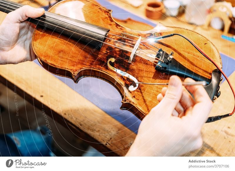 Anonymous luthier installing sound post to violin insert make instrument artisan craft tool hand work setting workshop equipment cello skill master maker