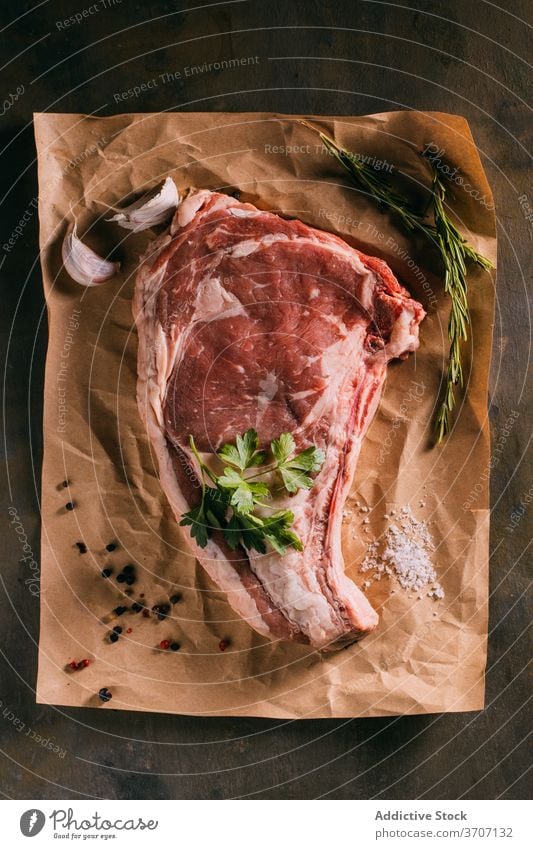 Raw meat on table with various ingredients raw beef condiment seasoning vegetable arrangement kitchen piece craft paper fresh olive oil leaves garlic culinary