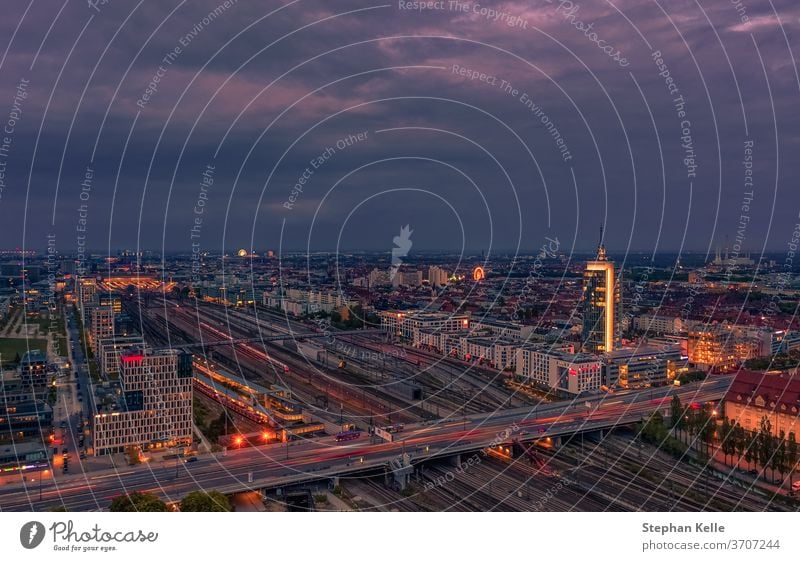 View over Munich at rush hour at the Donnersberger bridge with lights of cars in high angle view. german office tower violett sky street evening trails jam