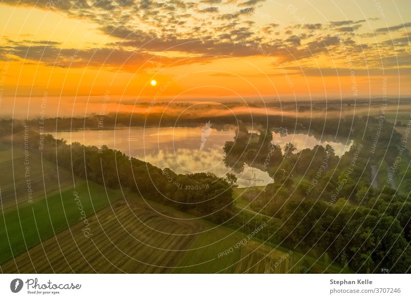 Germany, a powerful sunrise over a misty lake, pure nature moment. morning field sky background summer glow fog tree water orange beautiful landscape view