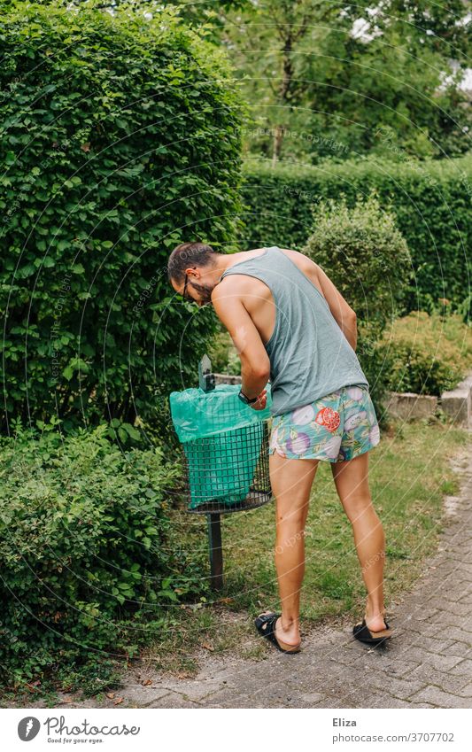 A man in summer clothes is looking for something in a dustbin by the wayside rubbish bin search Trash Human being Man Summer clothes inquisitorial Throw away