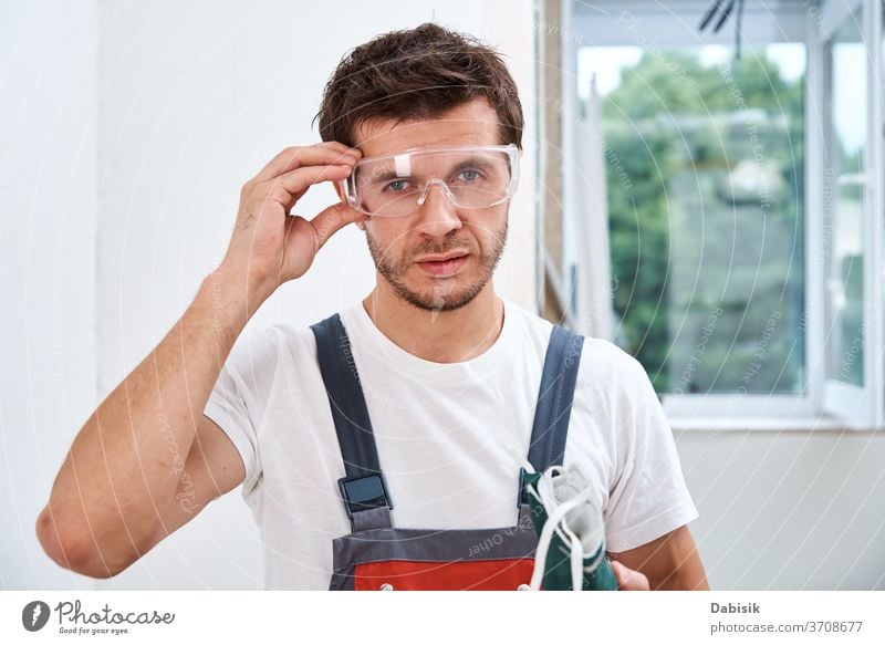 Portrait of home repair worker. Renovation handyman with protective glasses and respirator renovation protection builder construction male design wall