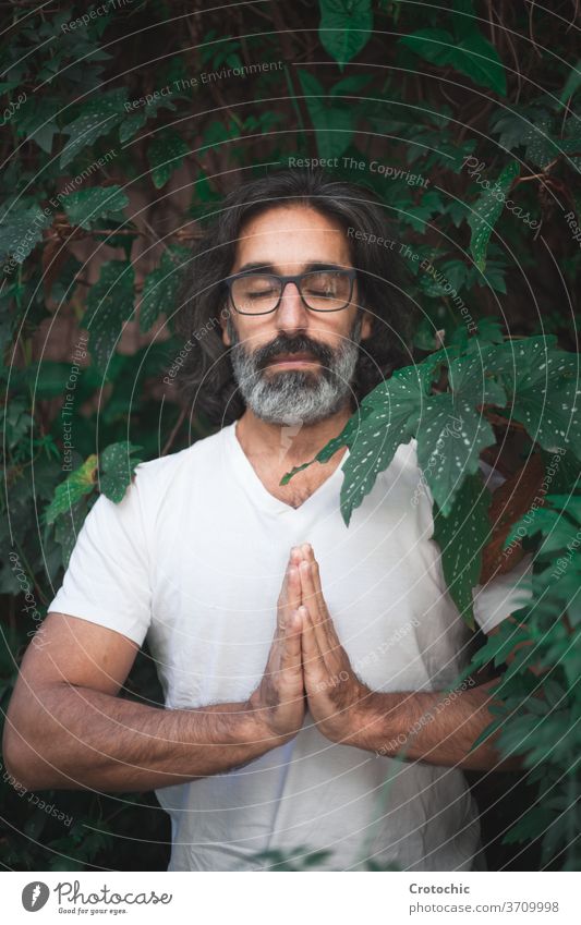 Man in white standing on a garden with his hands together in meditation hindu chakra meditating pray meditate balance pose man masculine comfortable pure grey