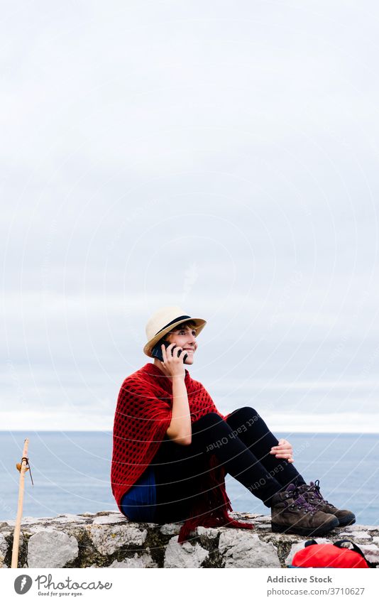 Female hiker using smartphone while resting near sea traveler woman pilgrimage backpack seaside browsing camino de santiago spain way route rural navigate check