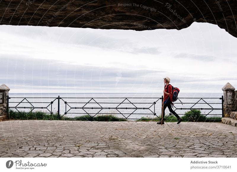 Female hiker walking on sea embankment woman pilgrimage camino de santiago backpack travel spain activity seaside way female asturias llanes lifestyle coast