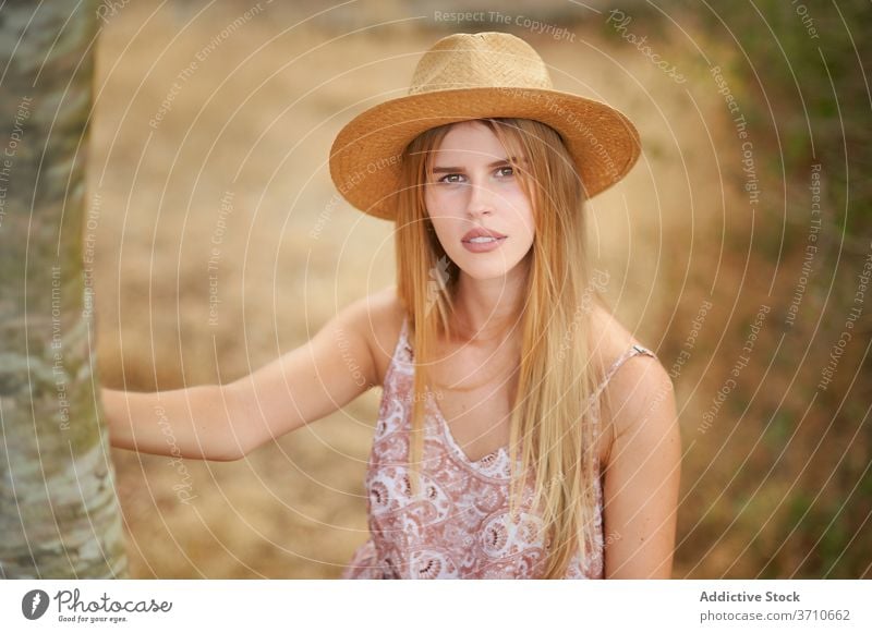 Stylish young woman standing near tree style dress hat nature summer blond charming portrait female beautiful fashion romantic sensual elegant outfit trendy