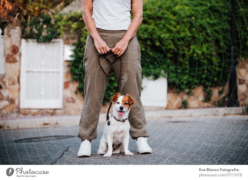 close up of young woman outdoors wearing protective mask, cute jack russell dog besides. New normal concept street new normal pet walking urban city lifestyle