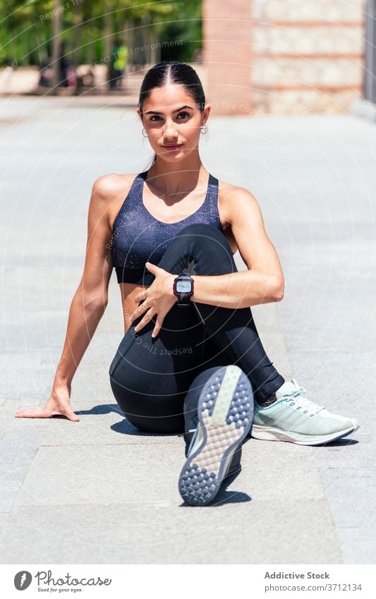 Determined woman warming up on street warm up stretch training city sportswoman flexible fit workout summer female athlete sportswear wellness pavement healthy