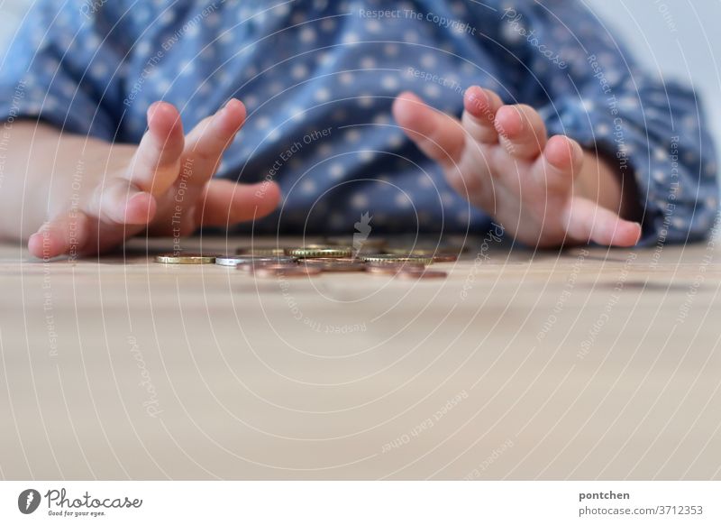 Pocket money. A child plays at a wooden table with coins, cents. Children's Hands Cent Euro Coin game curious explore children's hands Pattern points Money