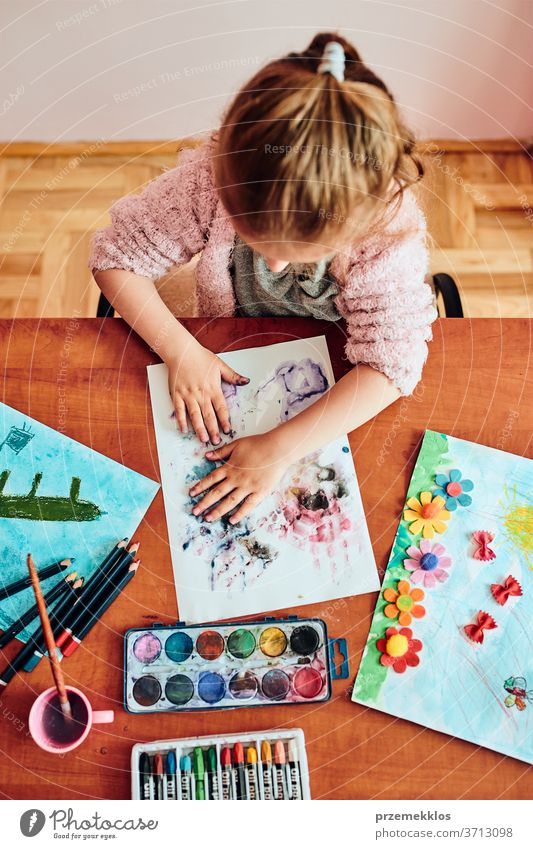 Little girl preschooler painting a picture using colorful paints and crayons. Child having fun making a picture during an art class in the classroom child dye