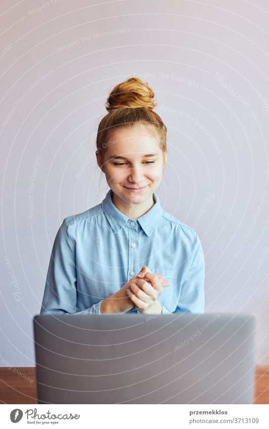 Young woman student having classes, learning online, watching lesson remotely, listening to professor, talking with classmates on video call from home during quarantine. Young girl using laptop sitting at a desk