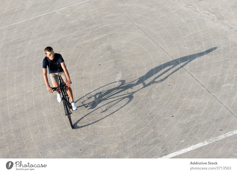 Young man riding bicycle on the street adult bike blond casual caucasian copy space ride cycling cyclist lifestyle male millennial mobility modern people